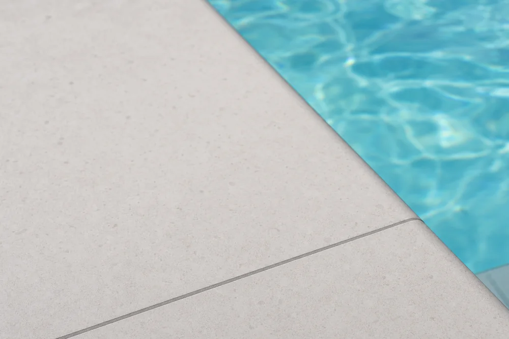 Heller Feinsteinzeug-Beckenrandstein mit sauberer Fuge am Pool
