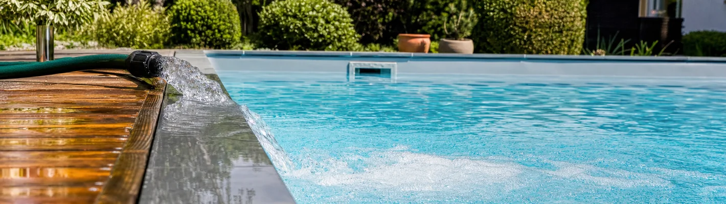 Frisches Füllwasser läuft über einen Gartenschlauch in einen Pool