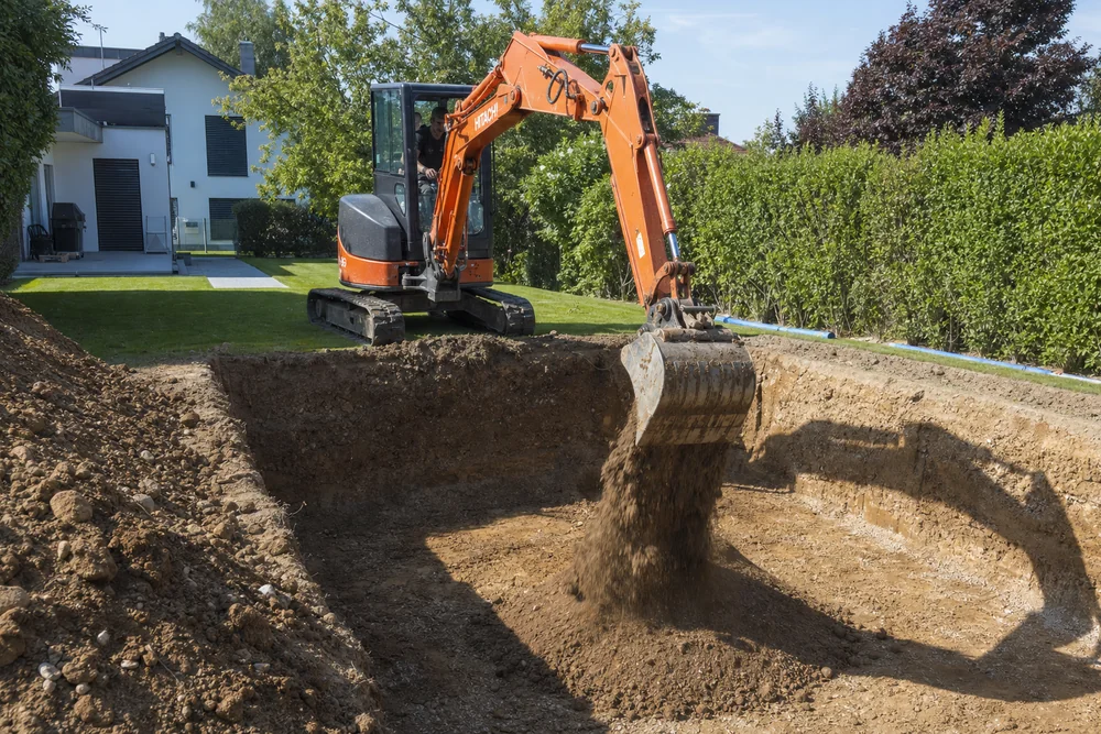 Aushub einer Poolgrube mit Bagger auf einer Baustelle im Garten