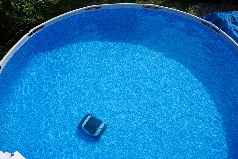 Blick von oben in einen runden Aufstellpool mit Poolroboter am Boden