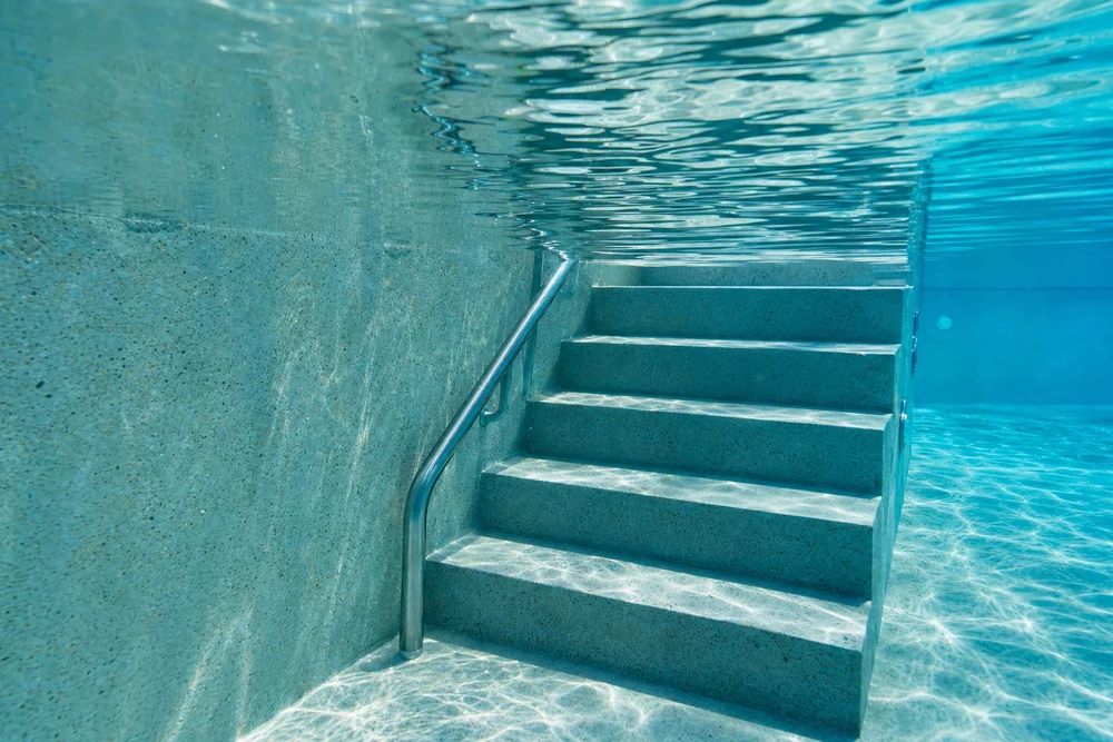 Schmale mehrstufige Beckentreppe mit Handlauf unter Wasser