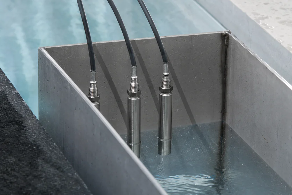 Tauchelektroden zur Niveauregelung hängen im Auffangbehälter eines Überlaufpools