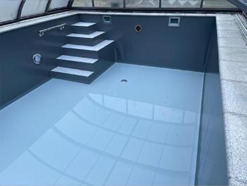 Pool in mit zweifarbiger Folie: dunkelgraue Beckenwände und hellem Boden, integrierte Treppe.