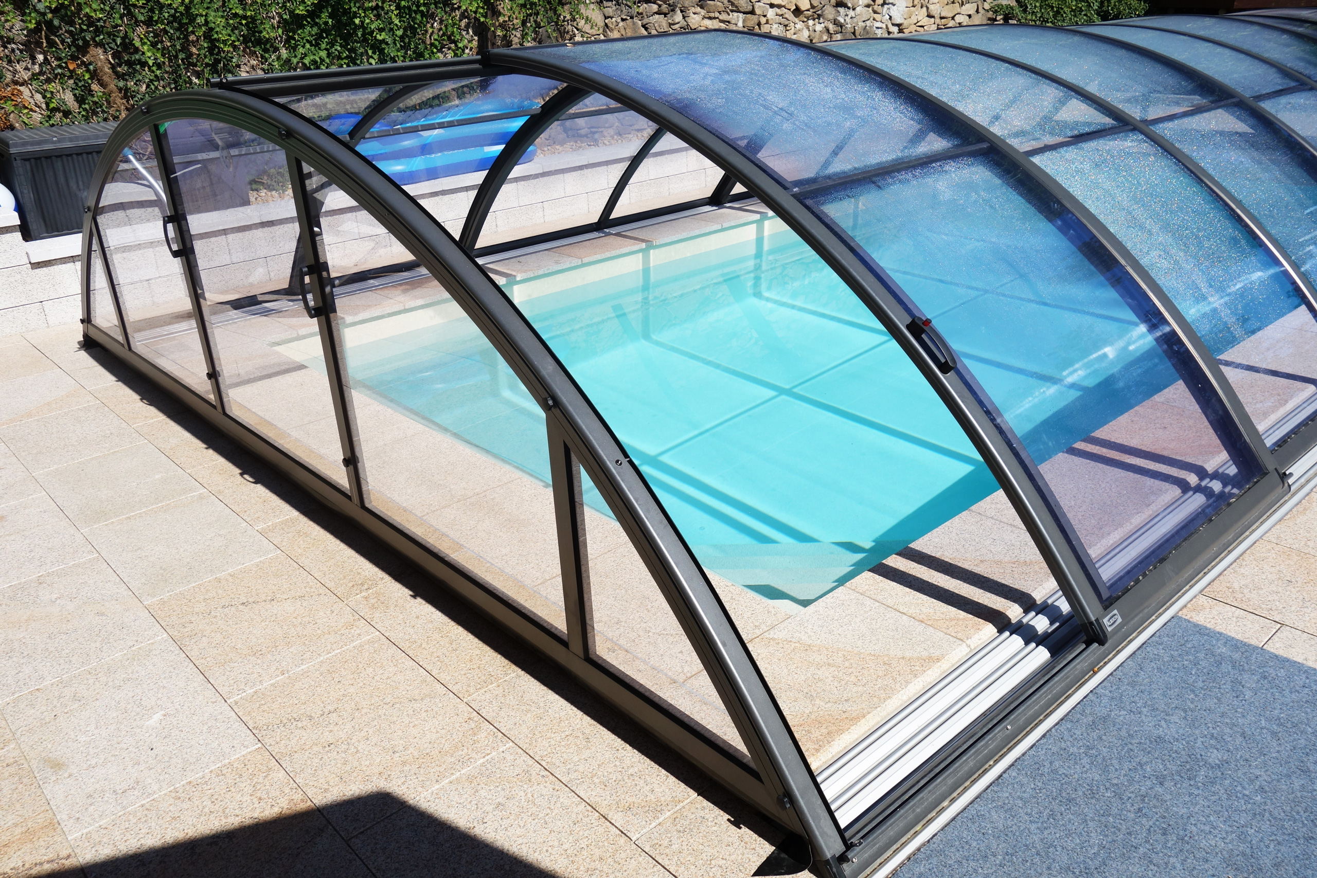 Detaillierte Ansicht der Poolüberdachung Klasik Clear mit transparenten Segmenten und Schiebesystem