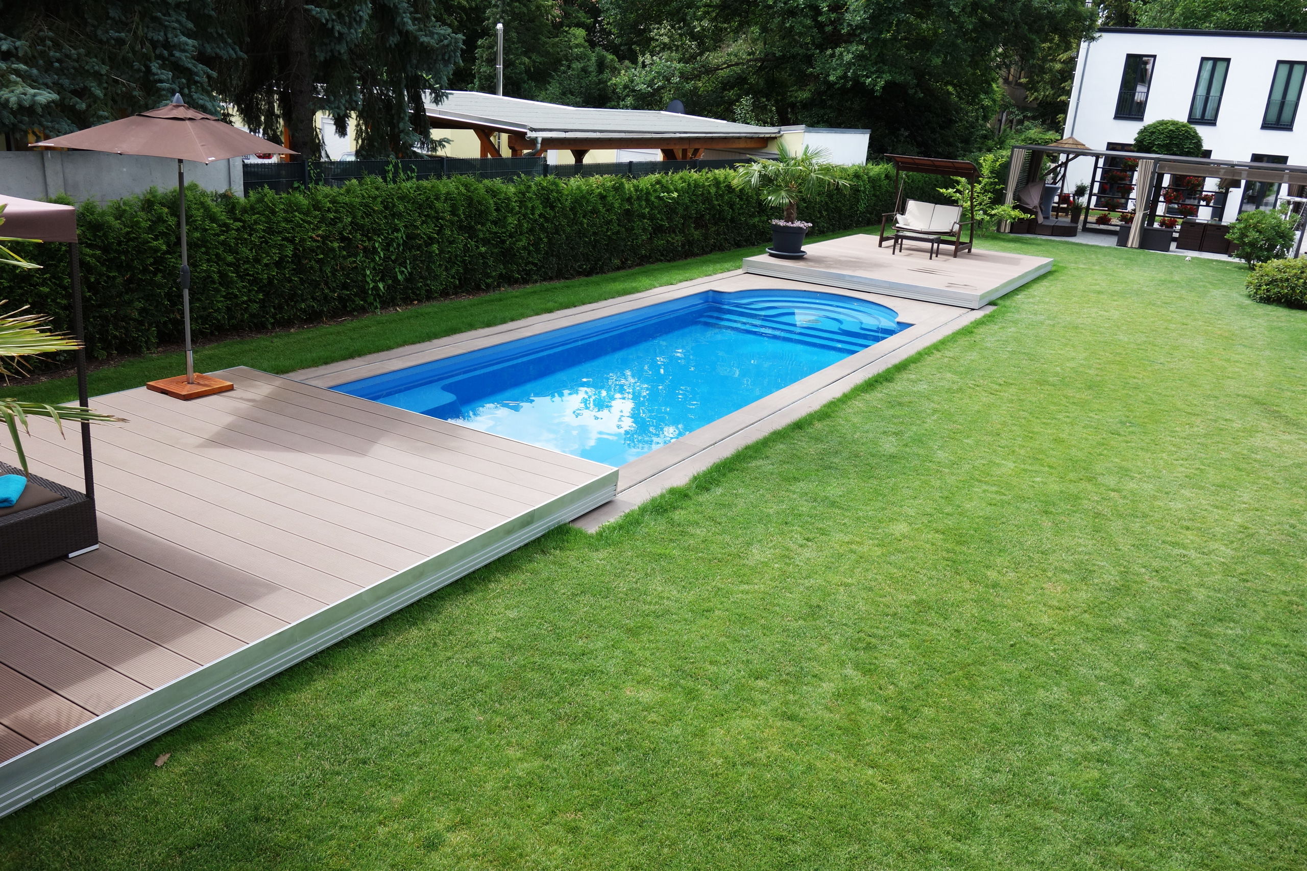 Compass Pool Schwimmbecken Java 101 mit Terrassenabdeckung und Liegeflächen im Garten