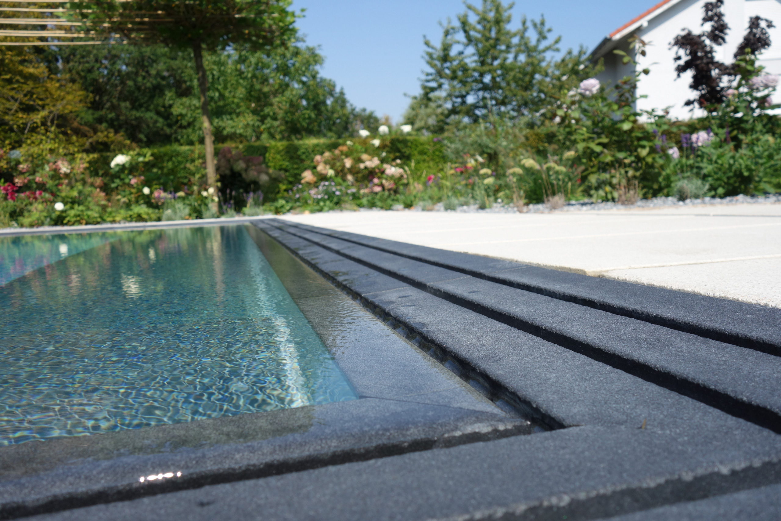 Detailansicht des Überlaufbeckens Overflow Stone mit Überlaufrinne und Poolwasser