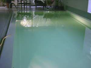 Hallenbad mit weißer Einhängefolie, die das Wasser in einem hellen Türkiston reflektiert.