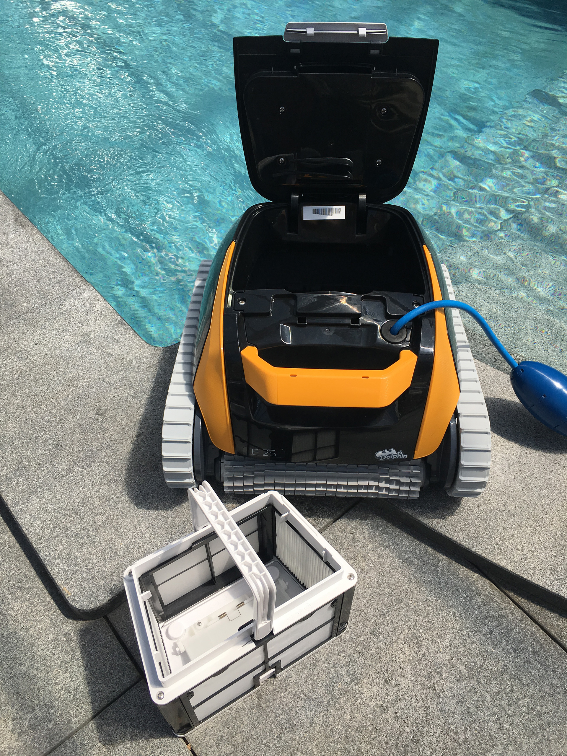 Dolphin E25 Poolsauger mit geöffnetem Filterfach und herausgenommenem Filterkorb am Poolrand