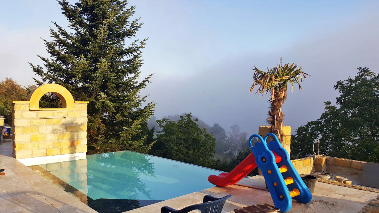 Überlaufbecken Infinity Pool 4x7x1,30m mit Ecktreppe und Sitzbank in Gartenlandschaft