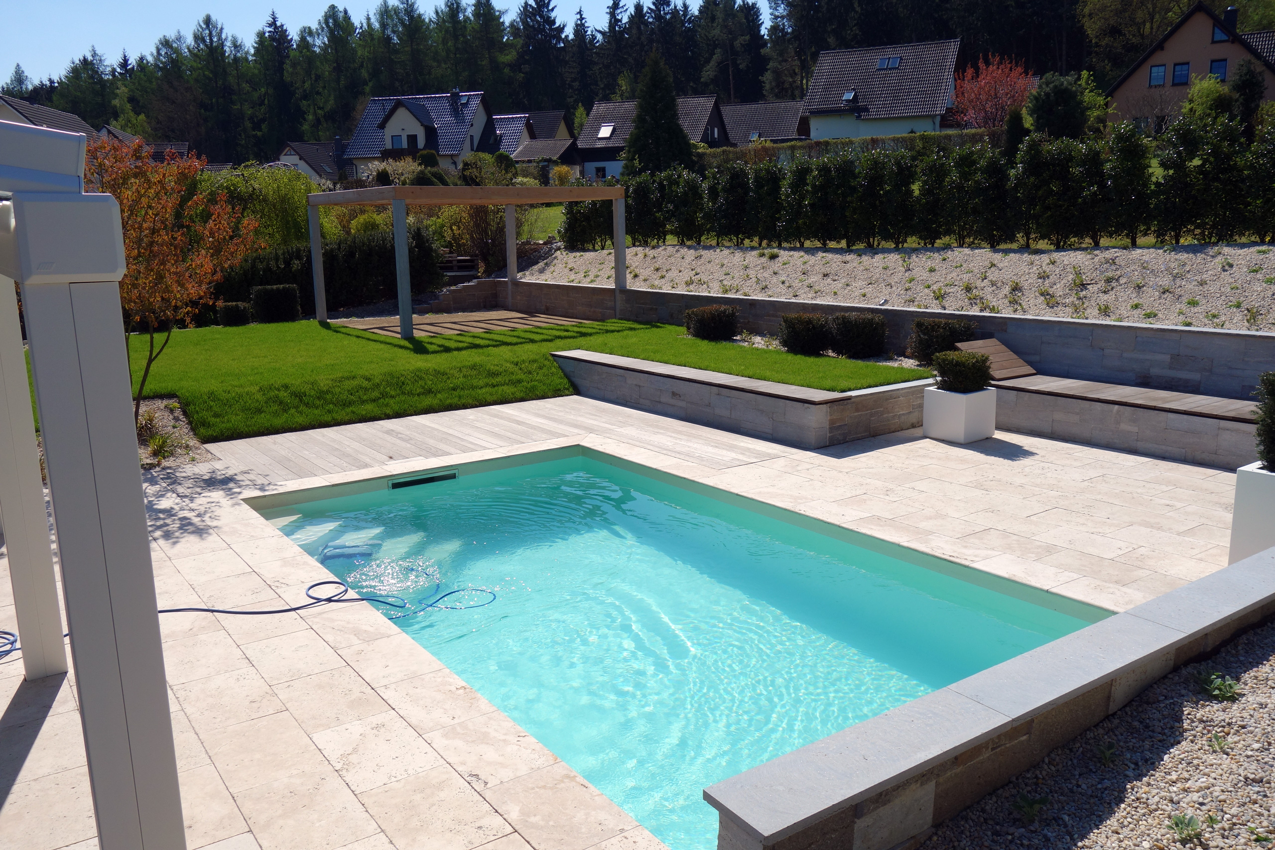 Schwimmbecken mit Strömungsturbine und Rollladenabdeckung in einer modernen Gartenanlage