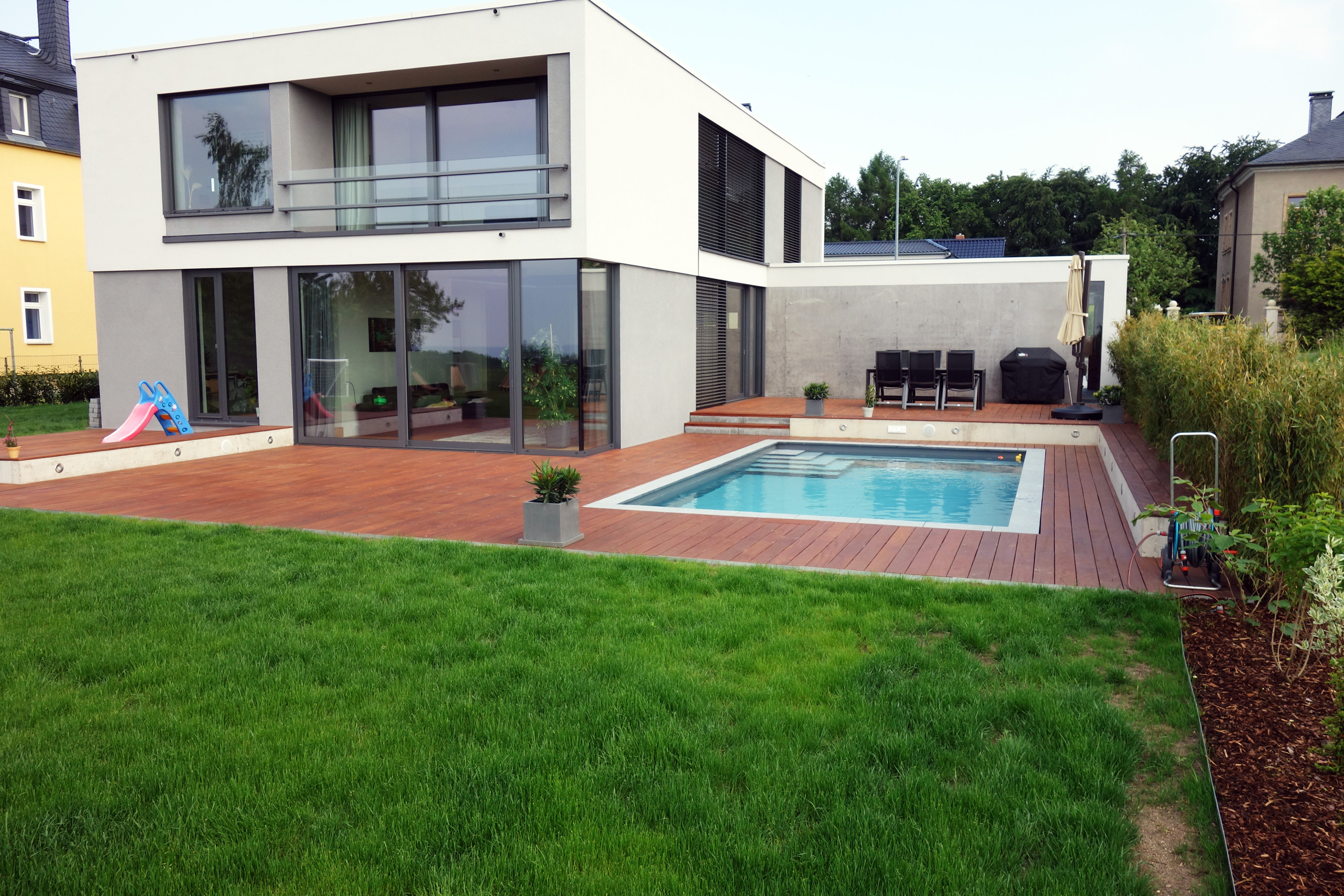 Betonbecken 3,5x7x1,5m mit Ecktreppe und Podest in moderner Gartenanlage mit Holzterrasse