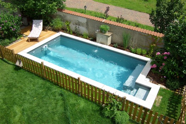 Rechteckiges Schwimmbecken 6x3x1,5 m mit integrierter Treppe, umgeben von Holzterrasse und Zaun