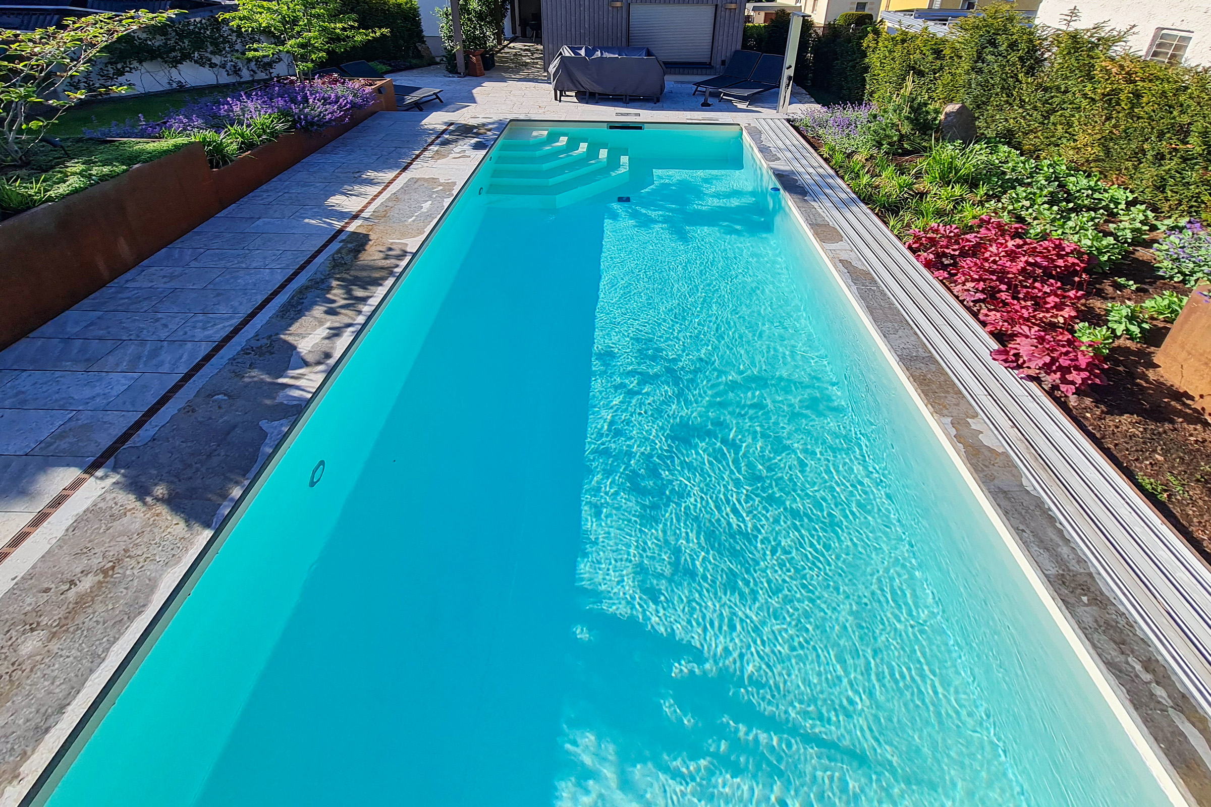 Pool mit Folienauskleidung in Pearl Sand in Hanglage Flacher Pool mit beiger Folienauskleidung in elegant strukturierter Gartenumgebung