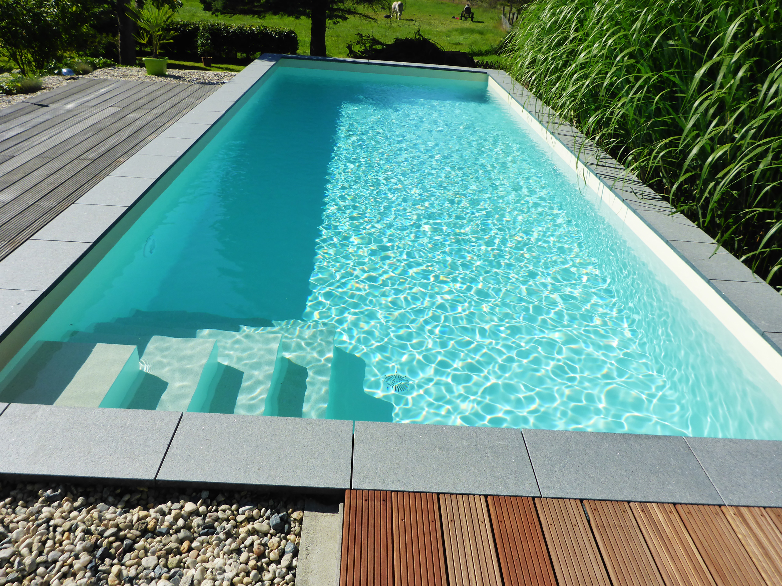 Blick auf den herausstehenden Swimmingpool mit Ecktreppe und Holzterrasse
