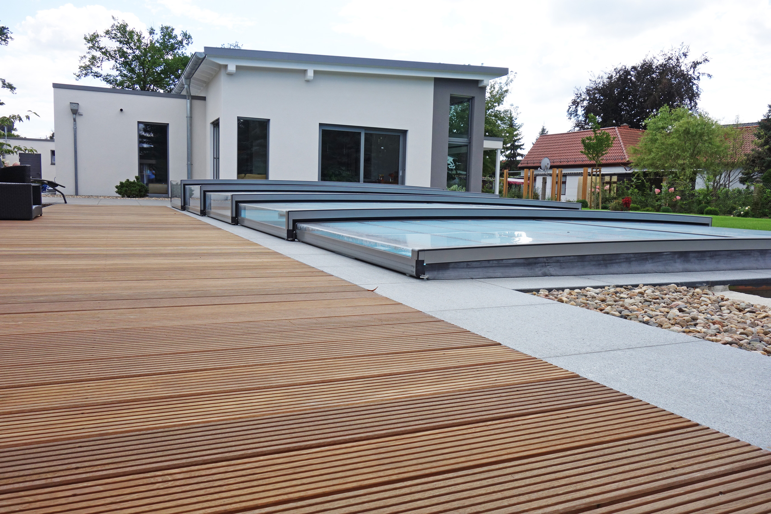 Holzterrasse mit Überdachung Horizont für den Außenpool und Kiesbett im Garten