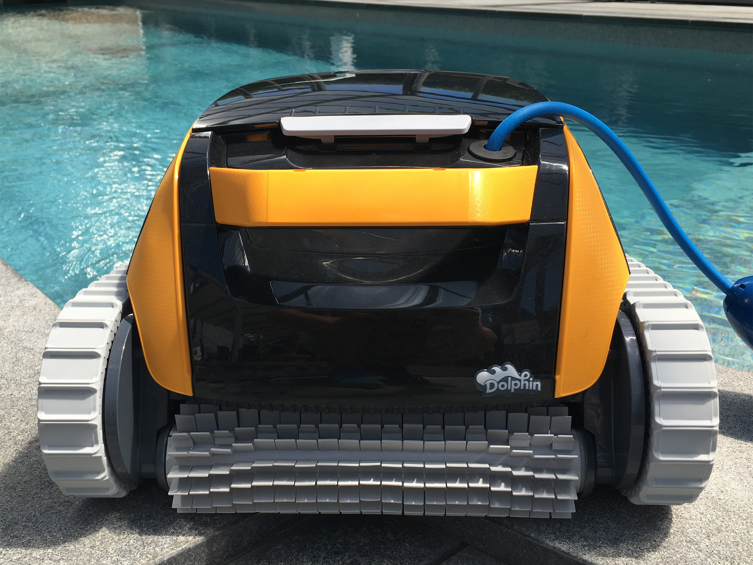 Dolphin E20 Poolroboter mit orangefarbenen Seiten, grauen Raupenbändern und Bürsten, von hinten am Poolrand