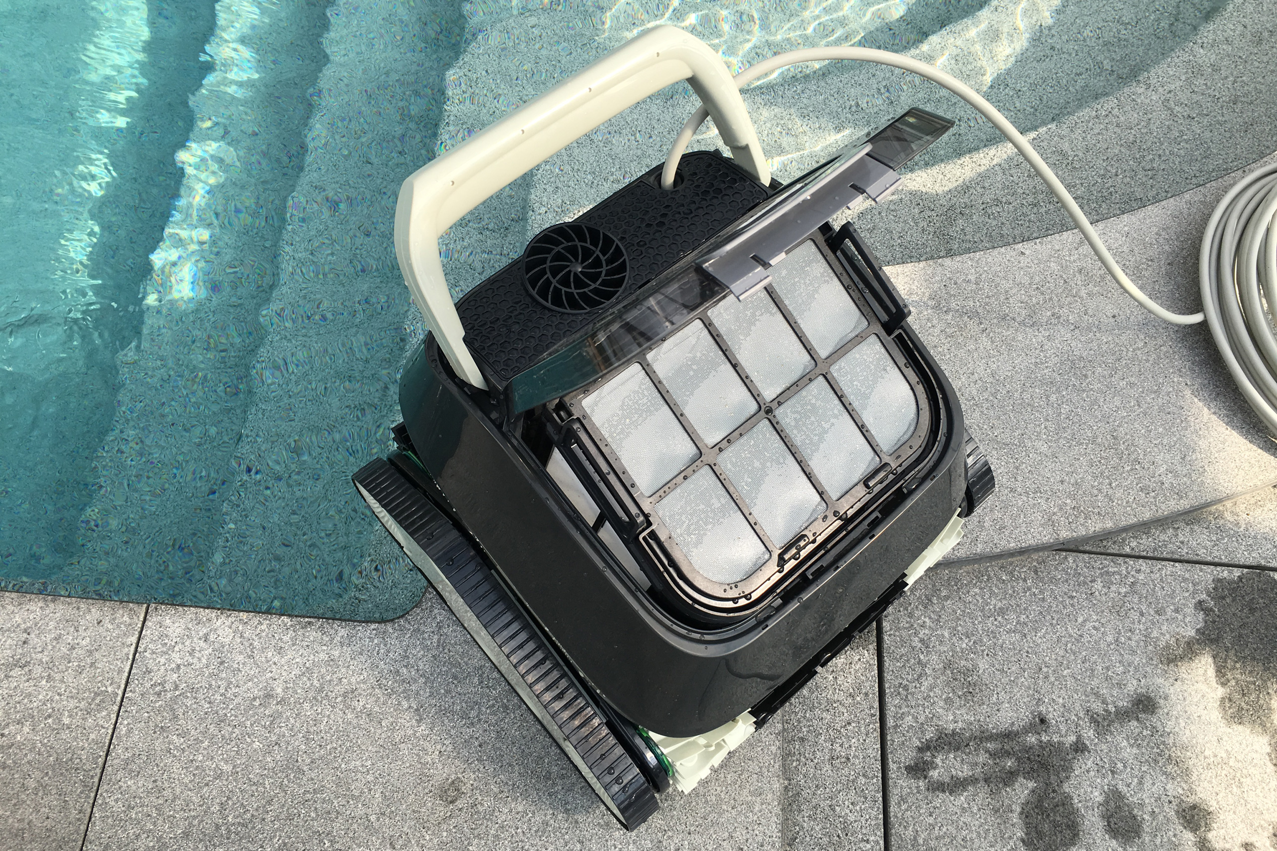 Geöffneter Pool Saugroboter Meranus POWER 4.0 mit sichtbarem Filterkorb und Kabel am Beckenrand