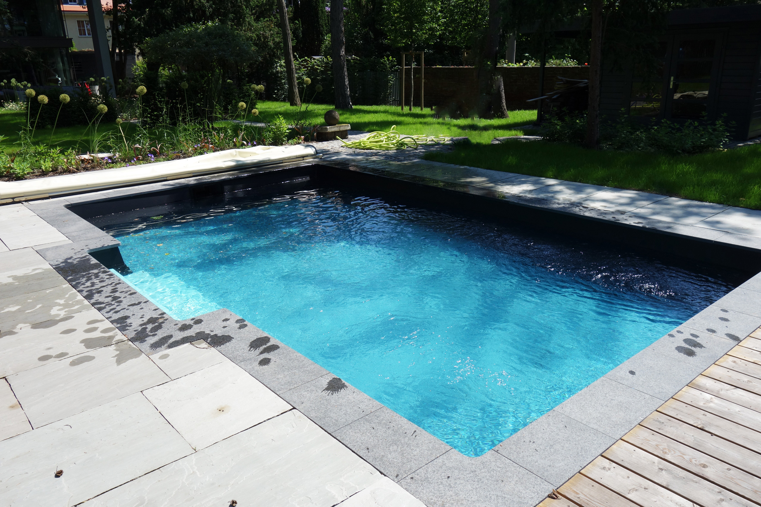 Rechteck-Pool 3,5x6x1,15m mit gerader Treppe, umgeben von Platten und Holzdeck, mit Poolabdeckung