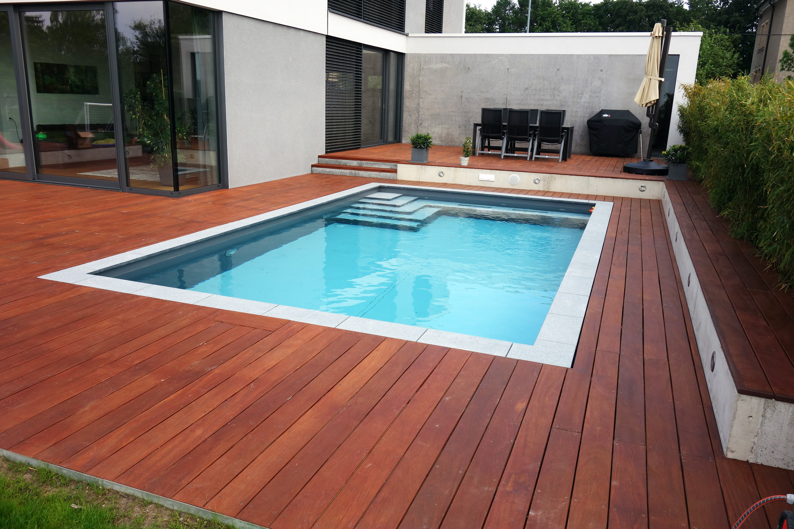 Betonbecken 3,5x7x1,5m mit Ecktreppe und Podest, umgeben von einer Holzterrasse