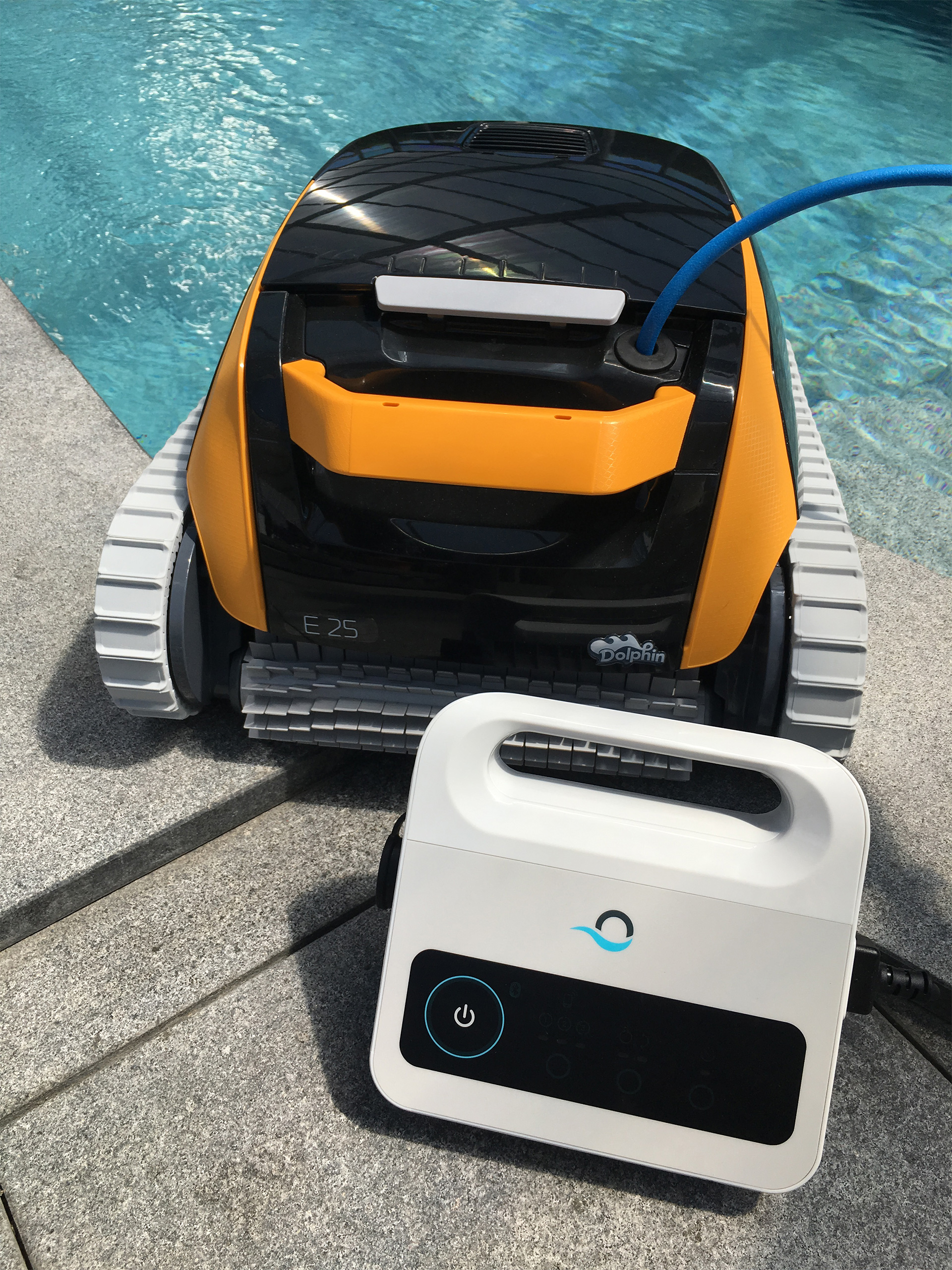 Dolphin E25 Poolsauger mit orangefarbenen Akzenten und weißem Netzteil am Poolrand
