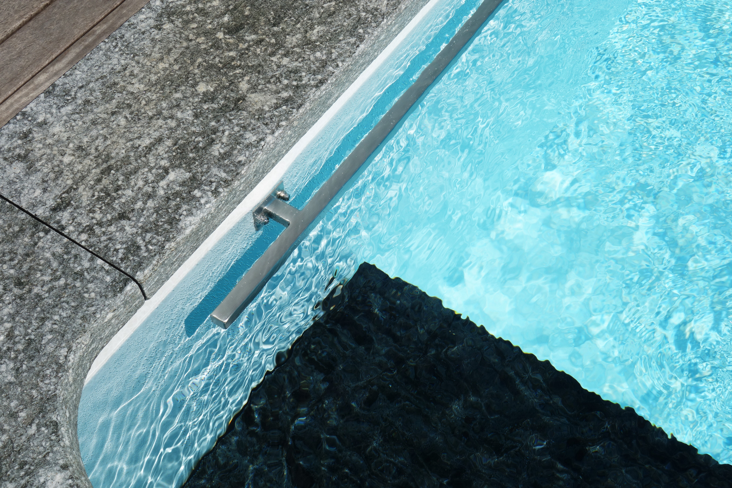 Detailansicht der Unterflurabdeckung im Pool mit blauer Folie und Steinrand