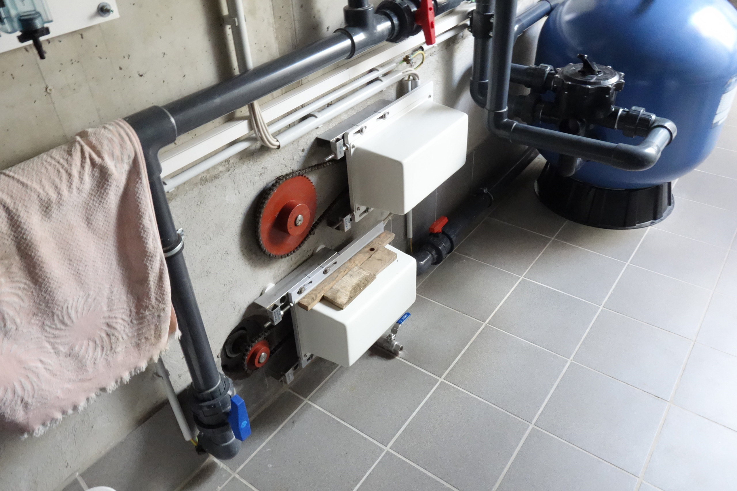 Detailansicht der Pooltechnik mit Filterkessel, Verrohrung und Abdeckung für die Rollladensteuerung.