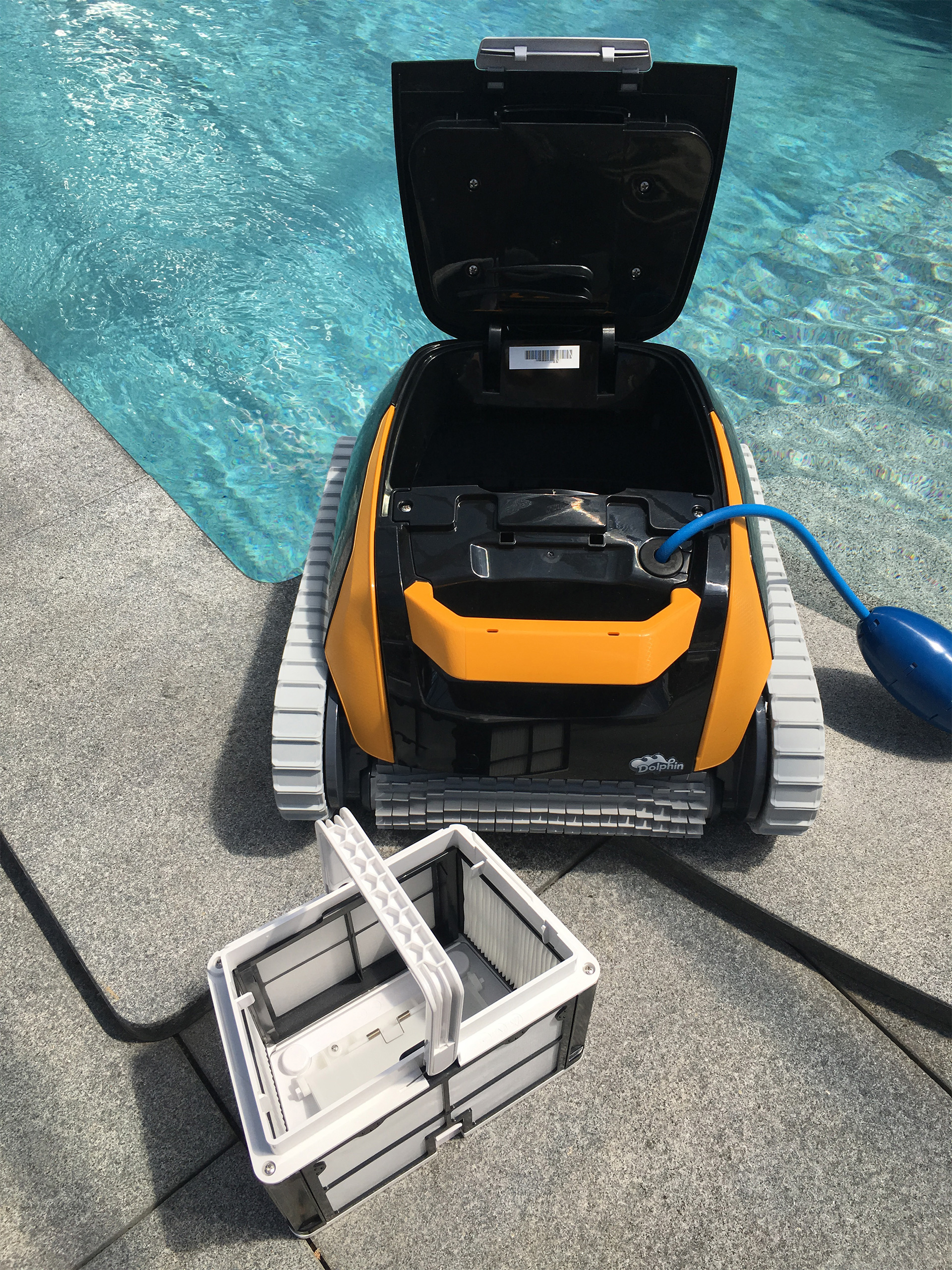 Geöffneter Poolroboter Dolphin E20 mit herausgenommenem Filterkorb am Poolrand