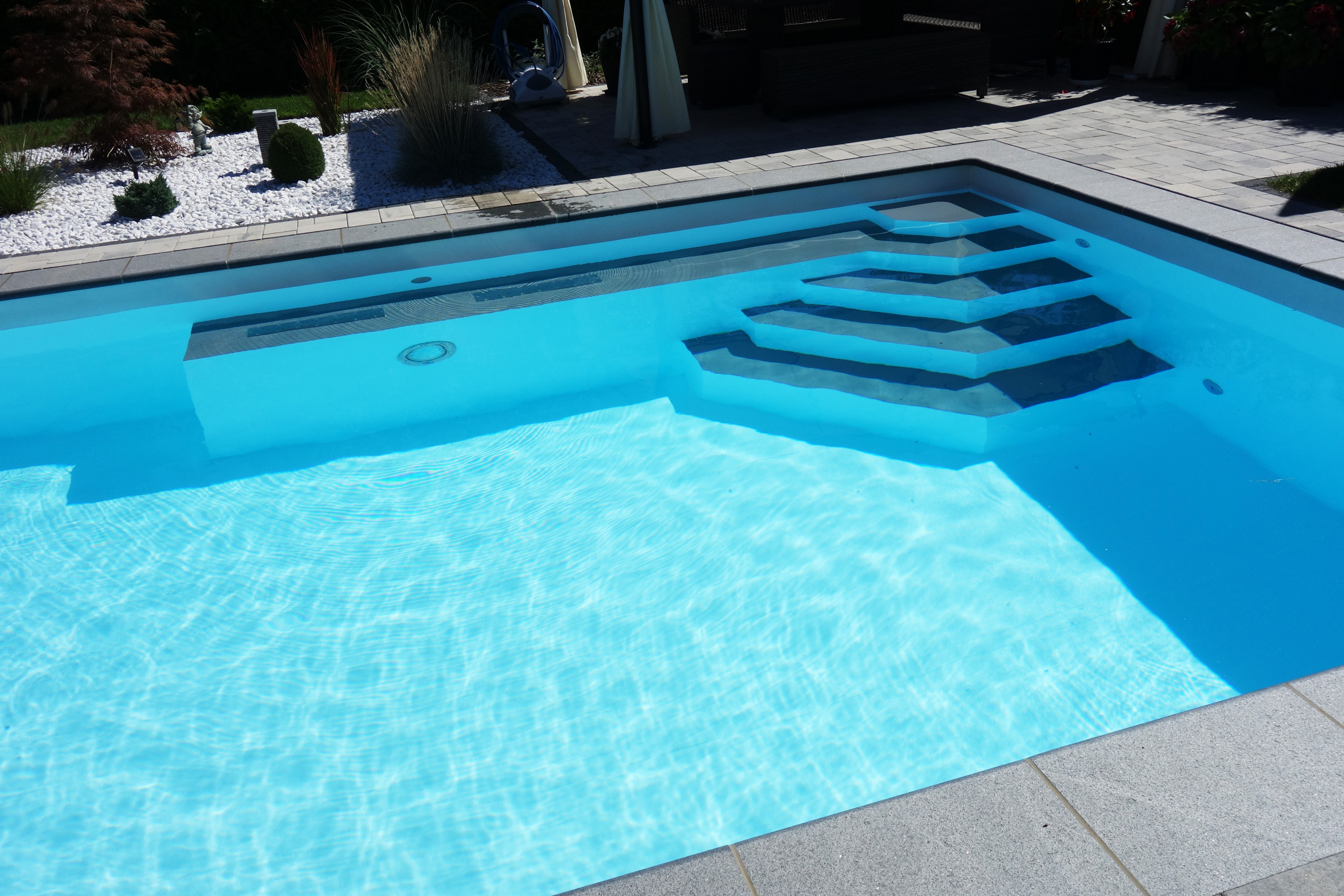 Blick auf die Ecktreppe, das Podest und den Luftsprudelsitz im Rechteckbecken mit blauem Wasser