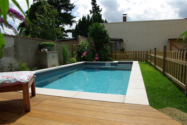 Schwimmbecken 6x3x1,5 m mit Treppe, umgeben von Holzterrasse, Rasen und Gartenbepflanzung.