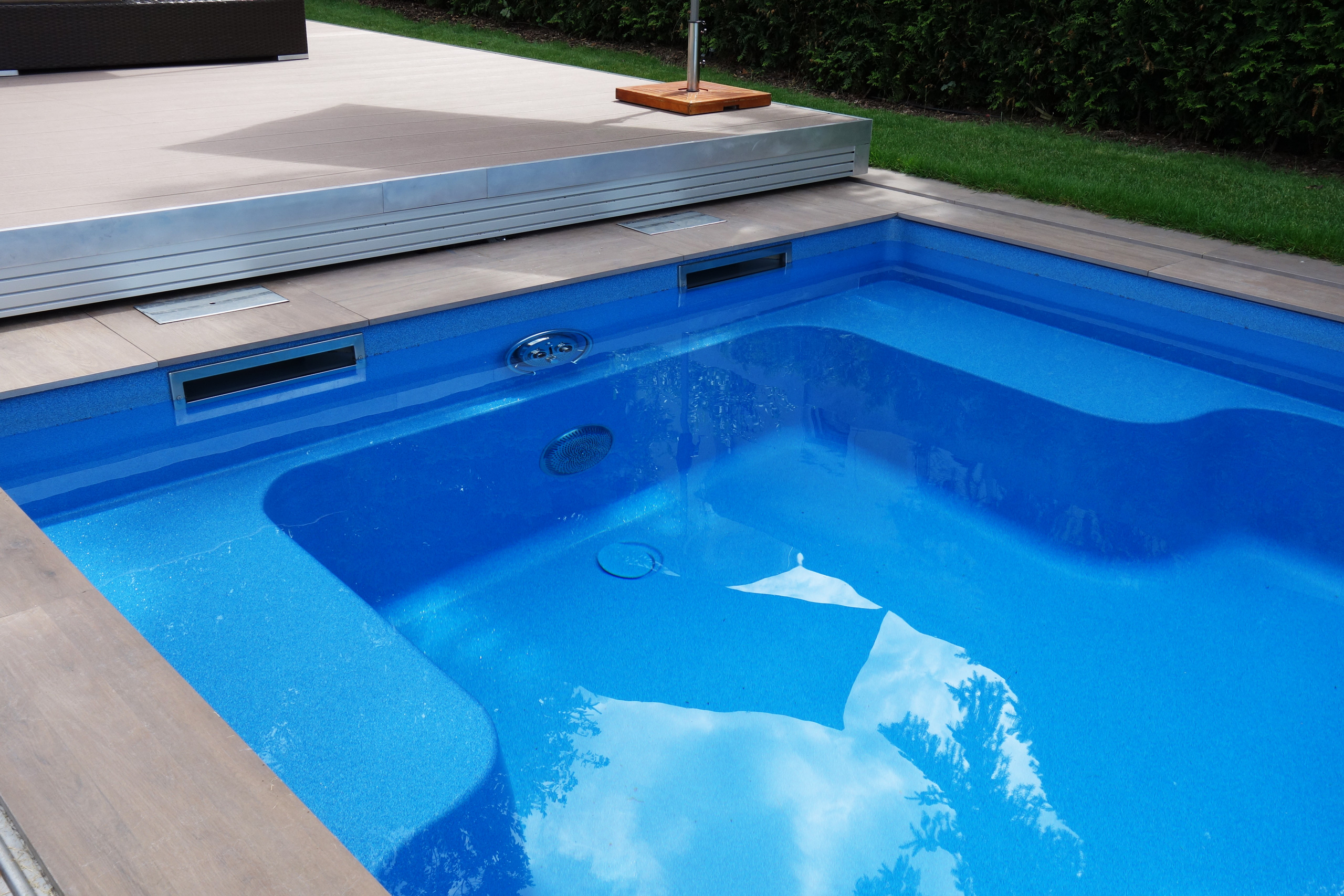 Detailansicht des blauen Compass Pool Schwimmbeckens Java 101 mit Terrassenabdeckung und Einbauteilen