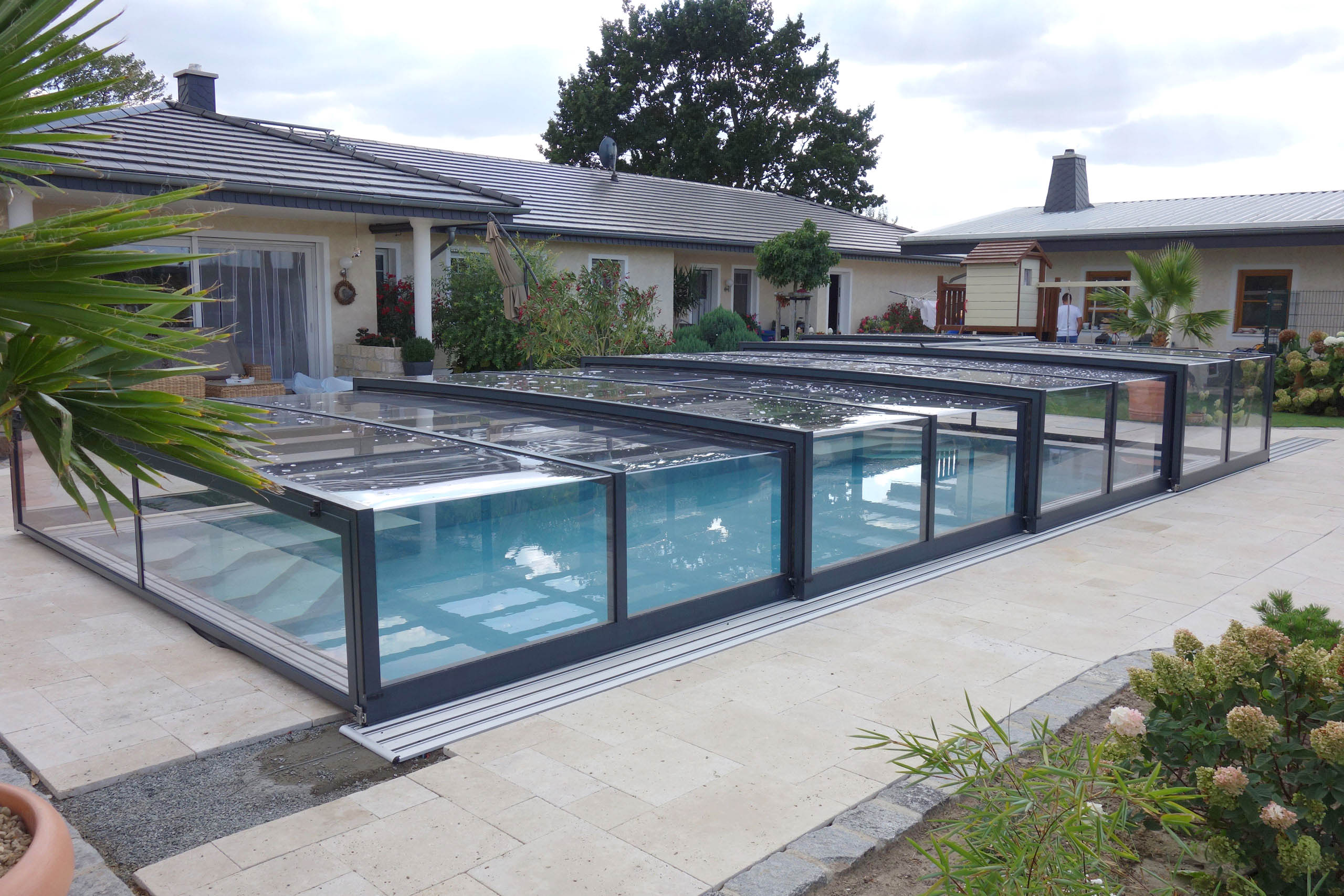 Poolüberdachung Prestige Plus mit Schiebeelementen über einem rechteckigen Pool im Garten