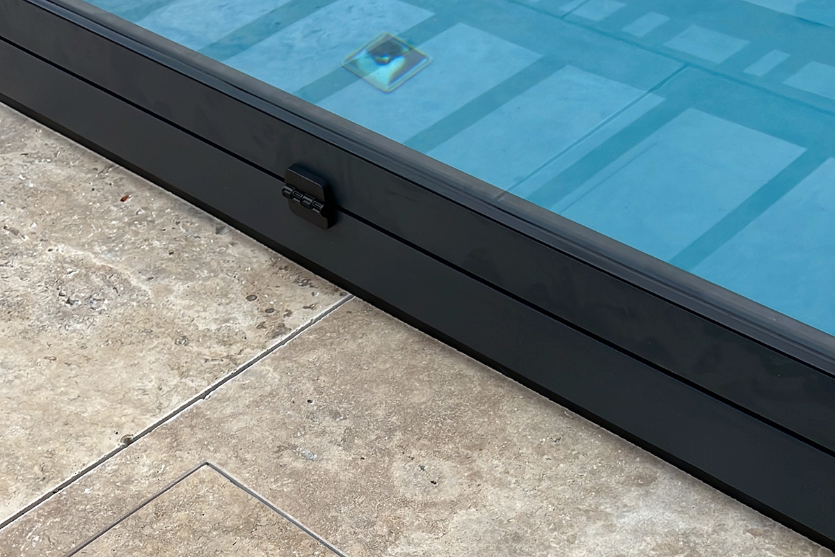 Detailansicht der flachen Poolüberdachung Aluna Exclusive Line R1 mit seitlicher Schiebetür und transparenten Segmenten.