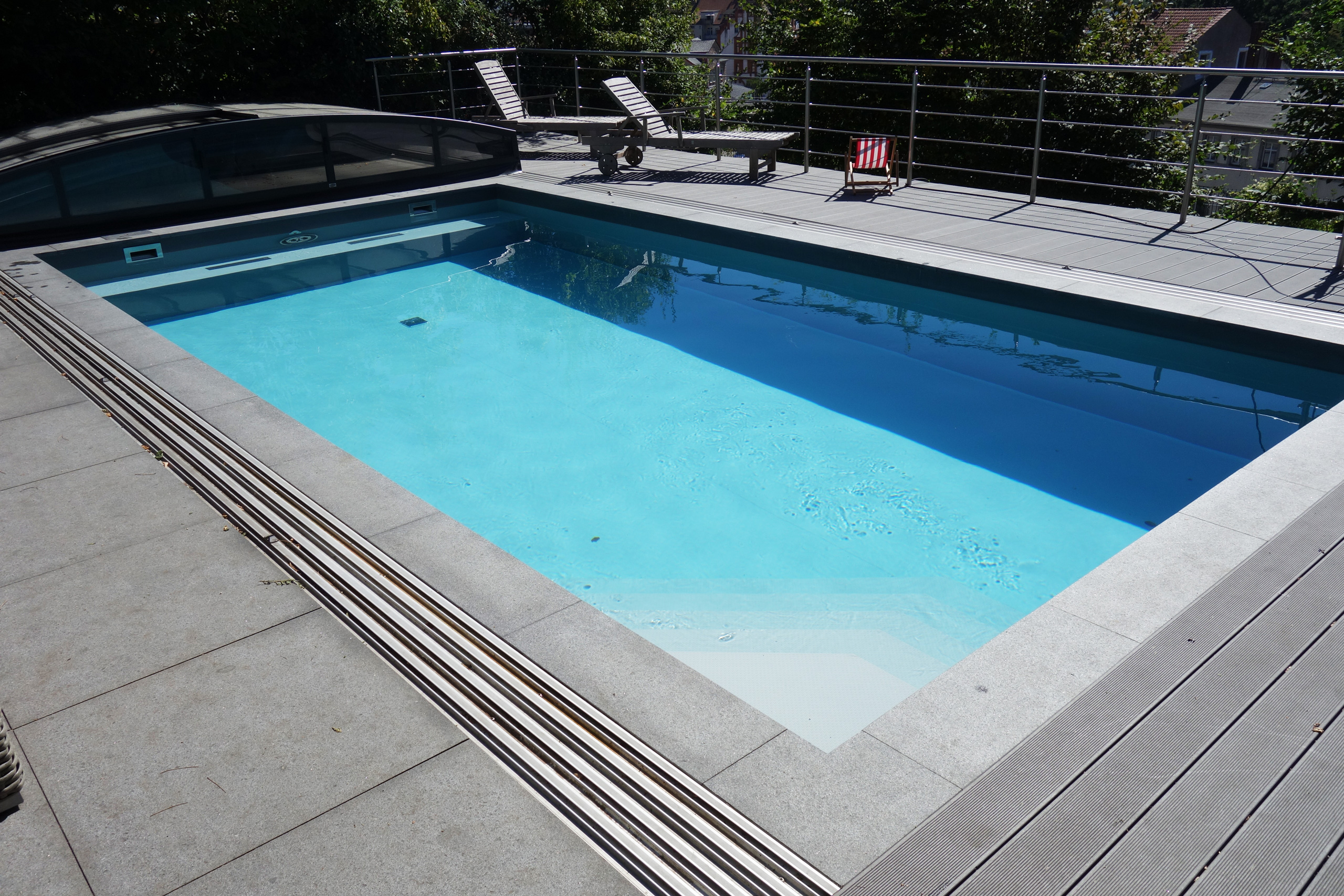 Betonbecken mit Überdachung, Ecktreppe, Sitzbank und Poolumrandung aus Stein und Holzverbund