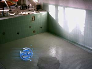 Leeres Hallenbad mit alten grünen Fliesen und vorbereitetem Boden für die Sanierung mit weißer Folie.