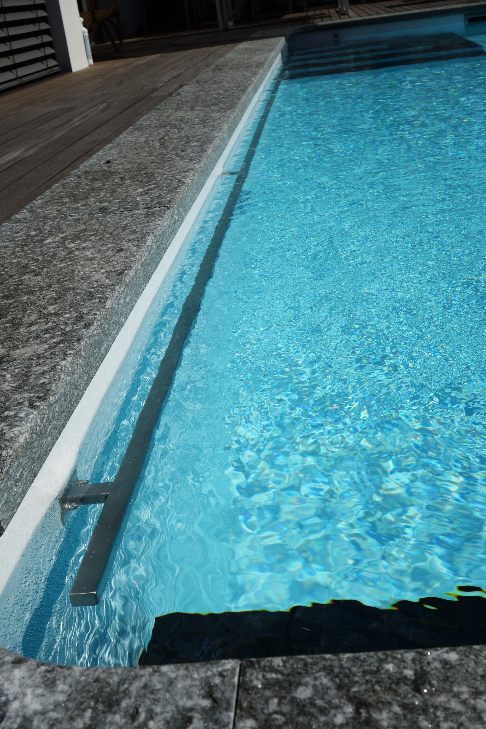 Detailansicht des Rechteckbeckens mit Unterflurabdeckung und blauer Wasseroberfläche