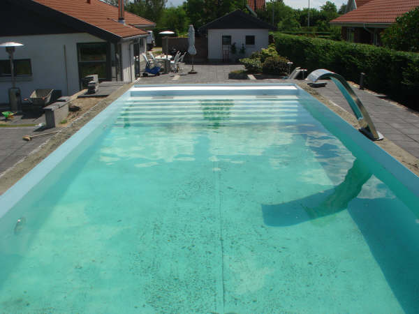 Pool mit integrierter Treppe, GSA-Abdeckung und einer eleganten Schwalldusche am Beckenrand.