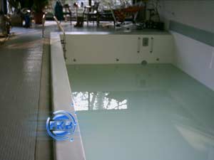 Hallenbad mit weißer Folie, das teilweise mit Wasser gefüllt ist, von der Seite aufgenommen