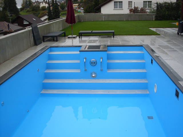 Gerade Treppe in einem blauen Schwimmbecken mit Edelstahl-Handläufen und Einbauteilen