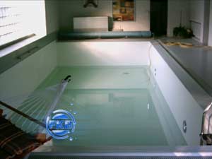 Leeres Hallenbad mit weißer Folie und teilweiser Wasserbefüllung, Blick auf die Pooltreppe