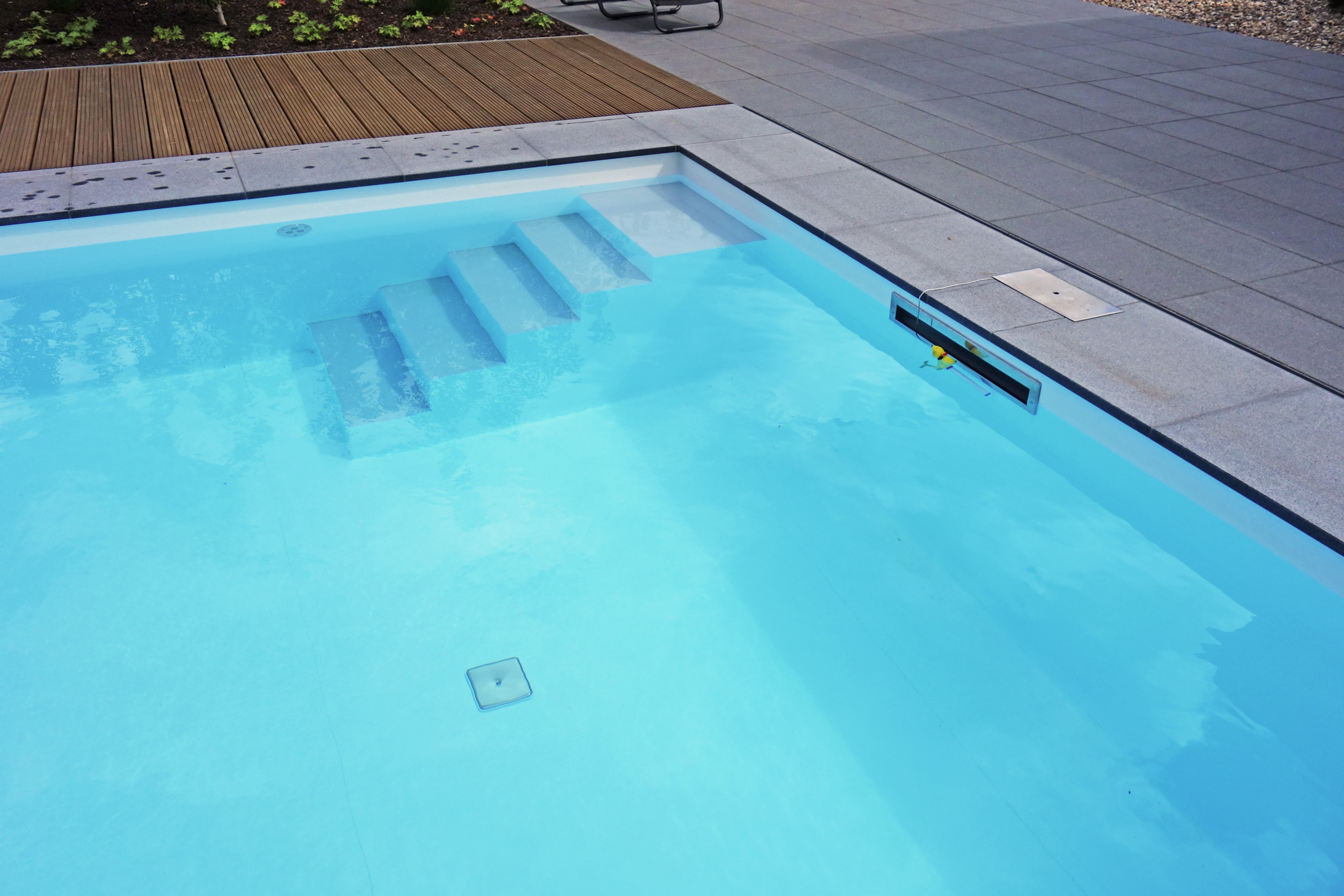 Gerade Treppe im Außenpool mit blauer Folie, umgeben von Holz- und Steinplatten