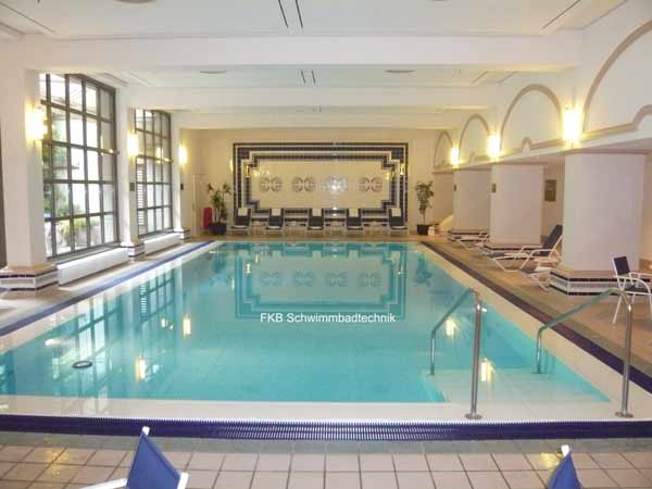 Innenpool mit Überlaufrinne und blauer Beckenfolie in einem großen Raum mit Fenstern und Säulen