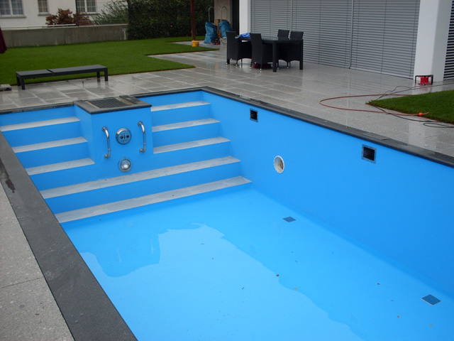 Gerade Treppe mit Haltegriffen und Einbauteilen in einem blauen Schwimmbecken