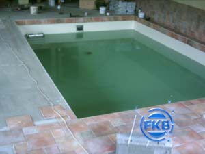 Hallenbad mit Folienauskleidung, teilweise mit Wasser gefüllt, umgeben von Fliesen und Baustelle