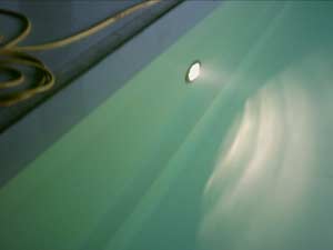 Unterwasser-Scheinwerfer im Hallenbad mit weißer Folie, das Wasser reflektiert das Licht.