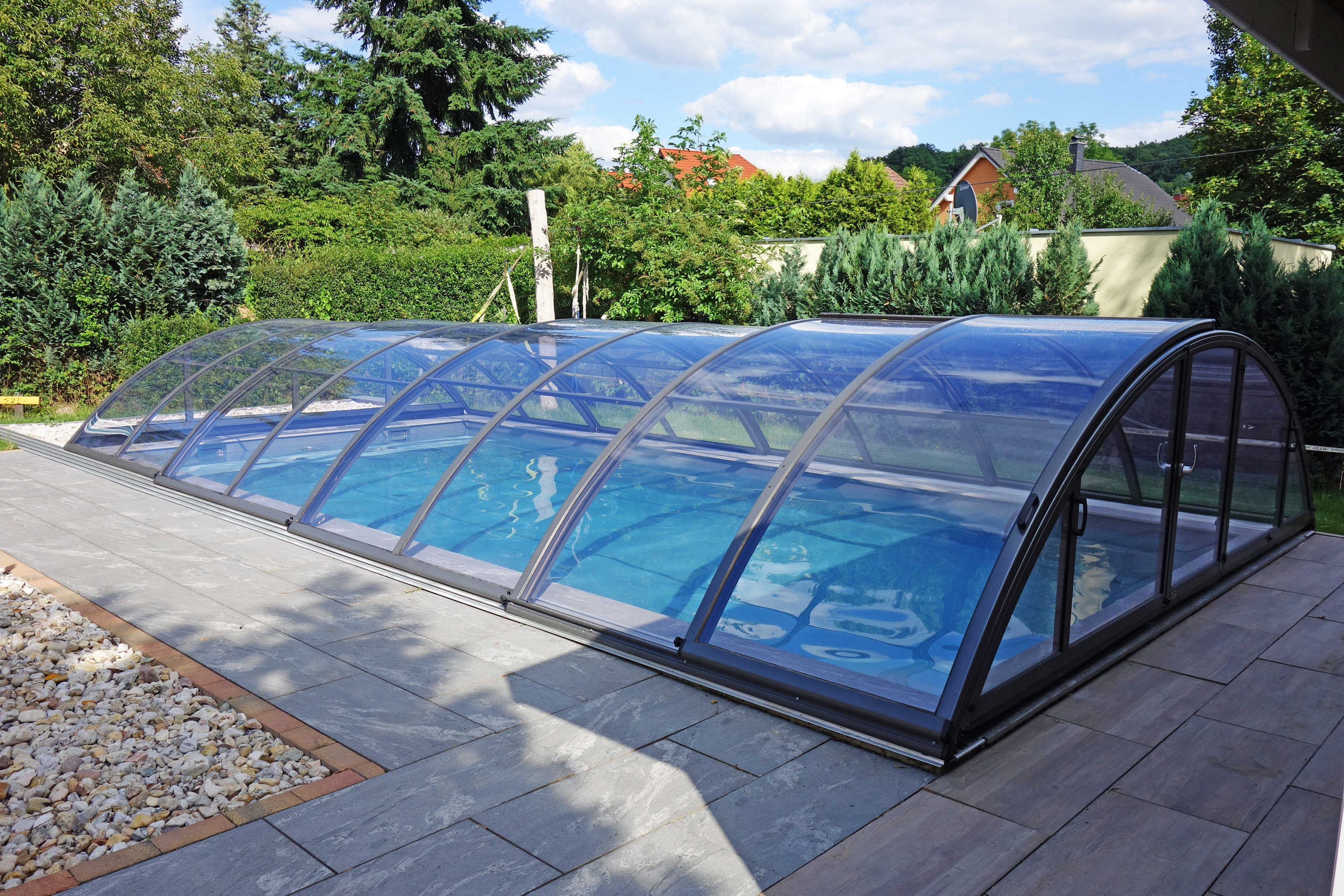 Schwimmbecken 4x8x1,5m mit Überdachung Premium B, umgeben von grauen Terrassenplatten und Kies