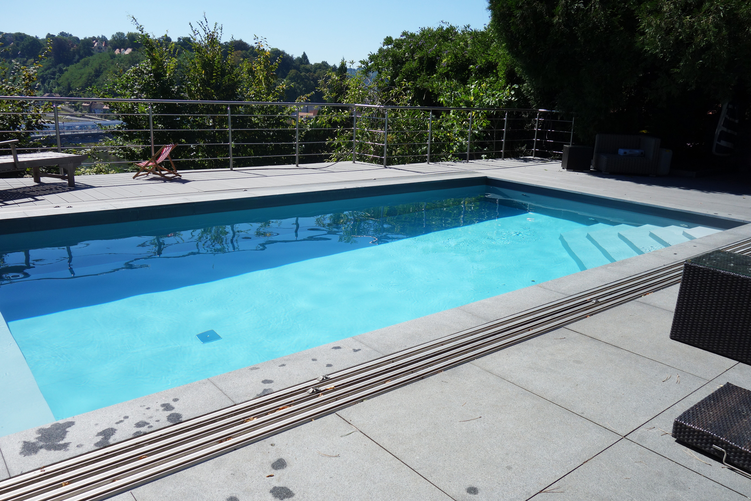 Detailansicht der Poolabdeckung mit Lamellen und der grauen Poolumrandung am Betonbecken