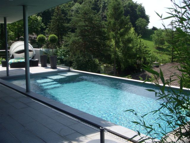 Langes Schwimmbecken mit Granit-Optik und Treppeneinstieg auf einer Terrasse mit Bergblick