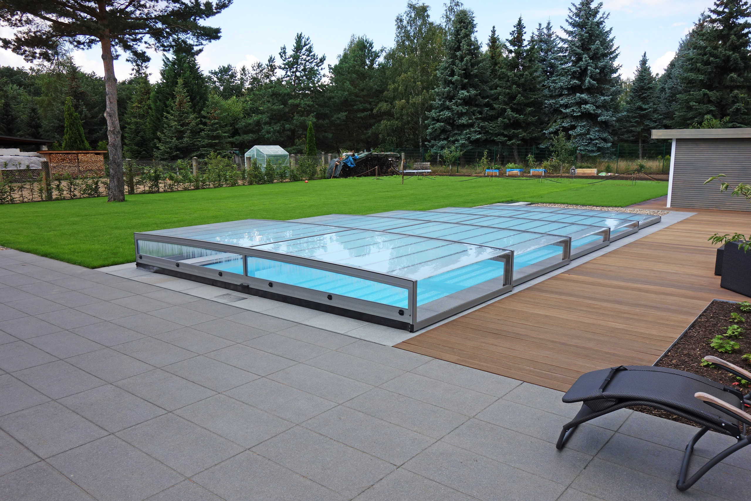 Außenpool 4x10x1,5m mit Überdachung Horizont, umgeben von Terrasse, Rasen und Bäumen