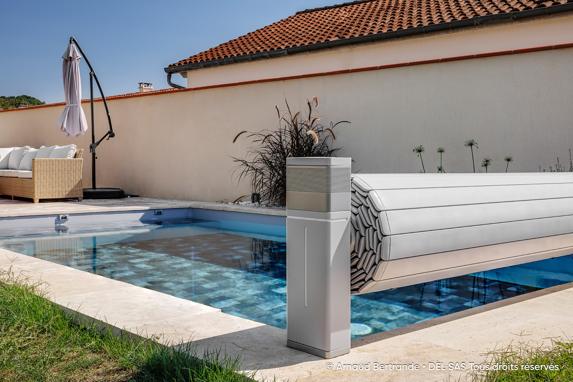 Grauer elektrischer Pool Aufroller Tixit mit Rollladenabdeckung an einem Pool im Garten