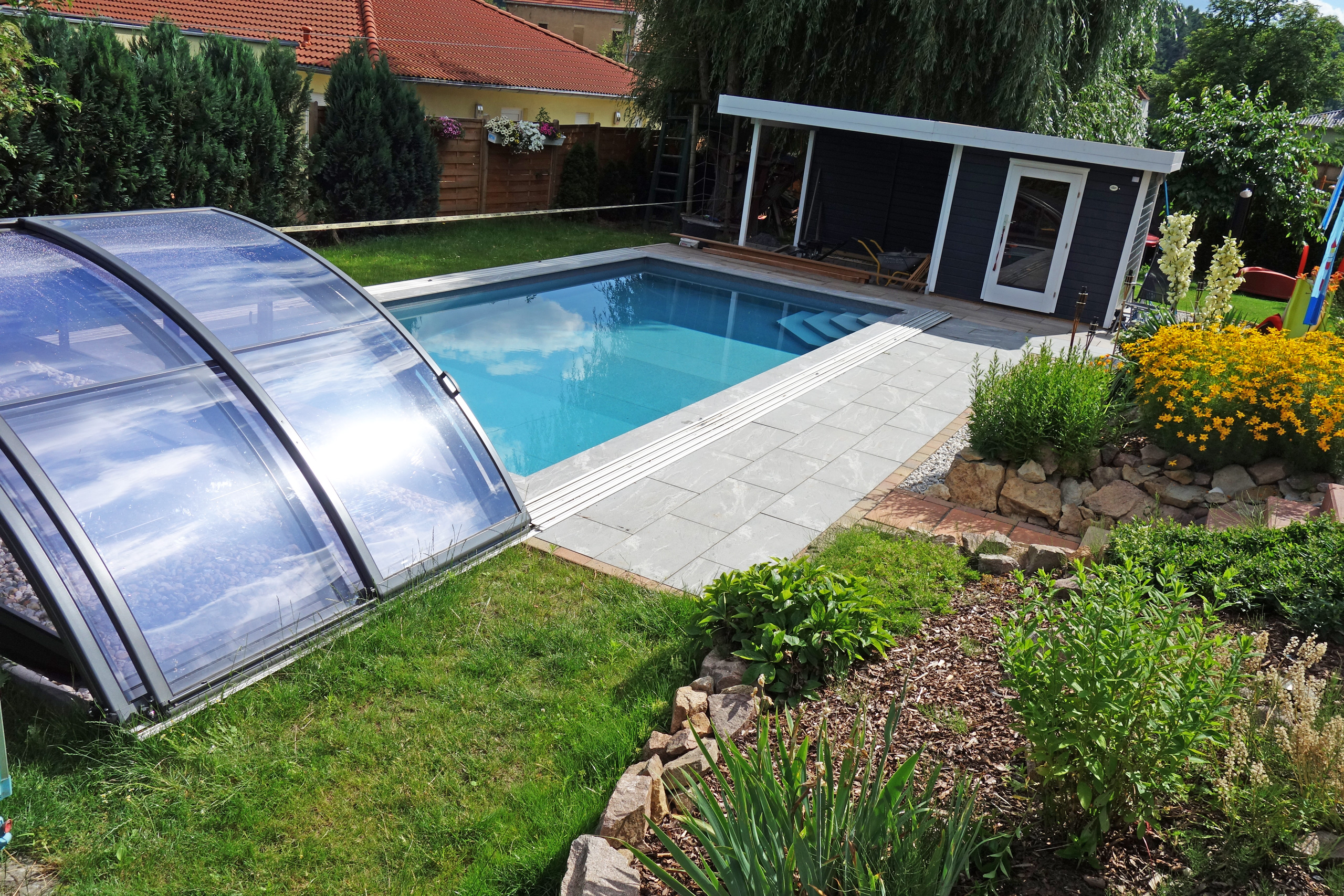 Schwimmbecken 4x8x1,5m mit Ecktreppe, Podest und Überdachung Premium B, umgeben von Garten und Schuppen.